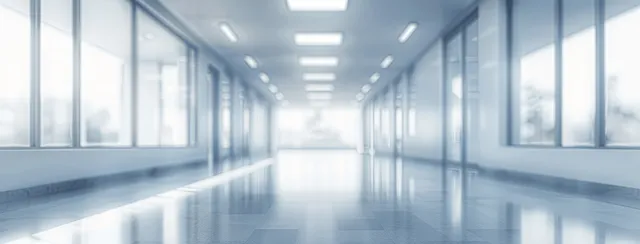 Empty modern hospital corridor with panoramic windows and soft daylight creating a blurred vanishing point.