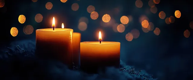 Candles burning in the dark with warm bokeh light and soft blue reflections