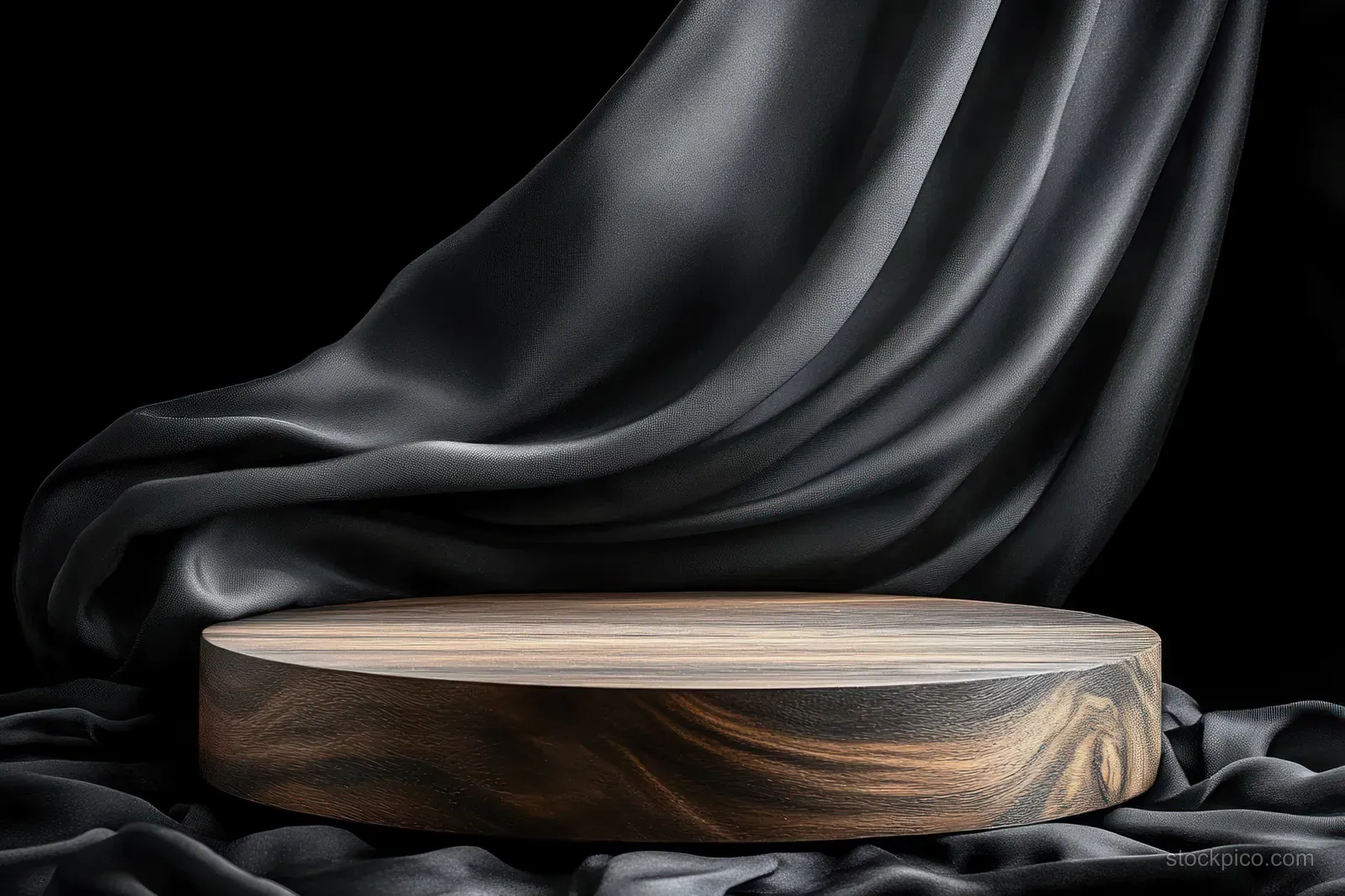 Wooden podium wrapped with flowing black silk fabric under a soft spotlight on a dark background.