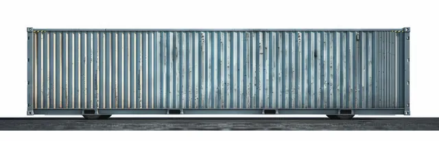 A long weathered blue shipping container on asphalt with rust streaks and peeling paint.