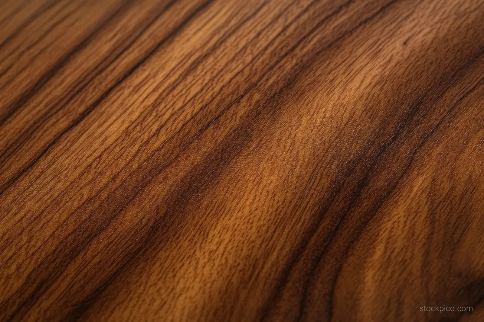 Polished walnut wood surface with swirling natural grain patterns in warm brown tones.
