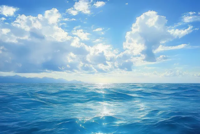 Vast blue ocean with small rolling waves, bright cloudy sky, and distant mountains on the horizon.