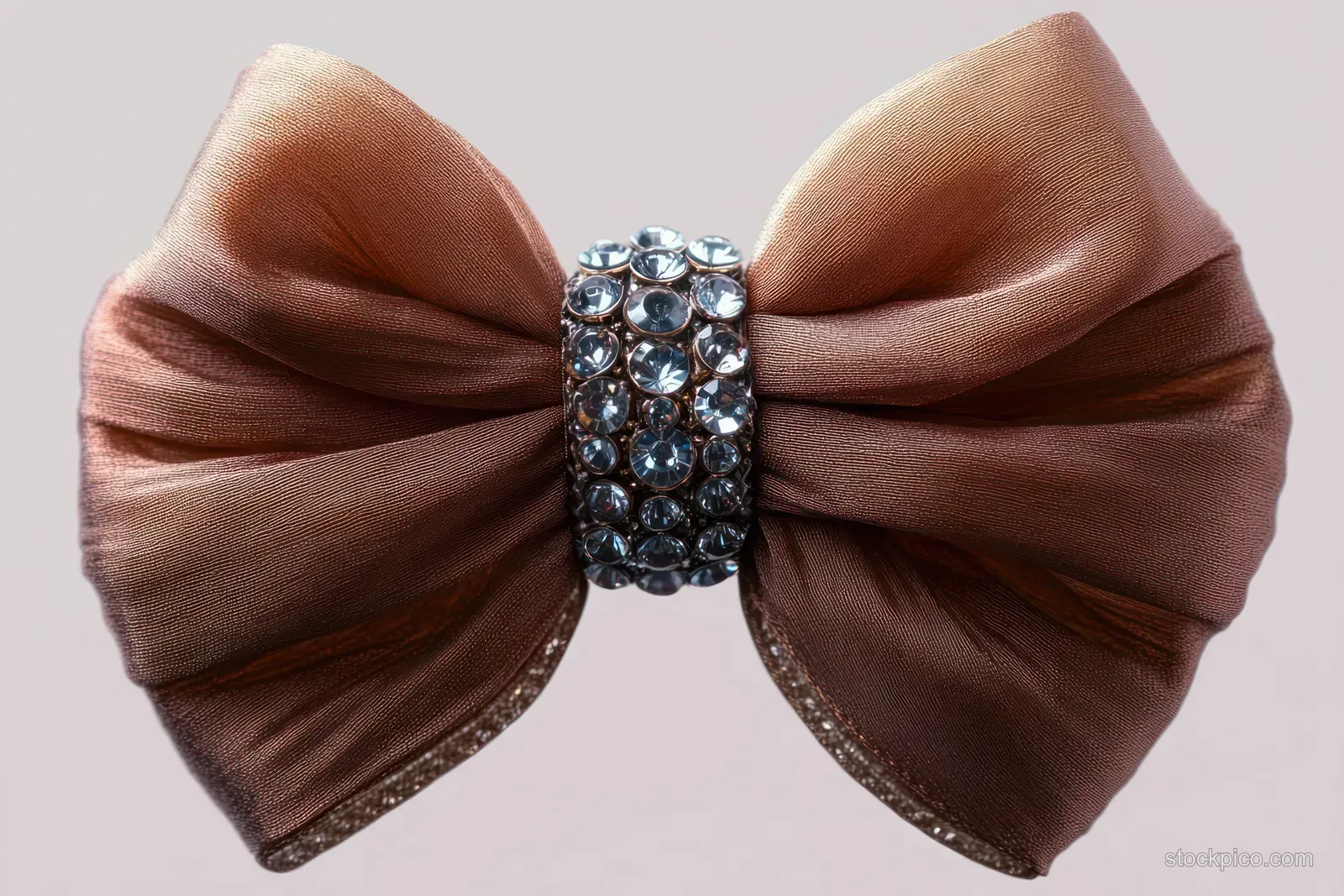 Brown satin bow tied with a rhinestone centerpiece on a soft neutral background.