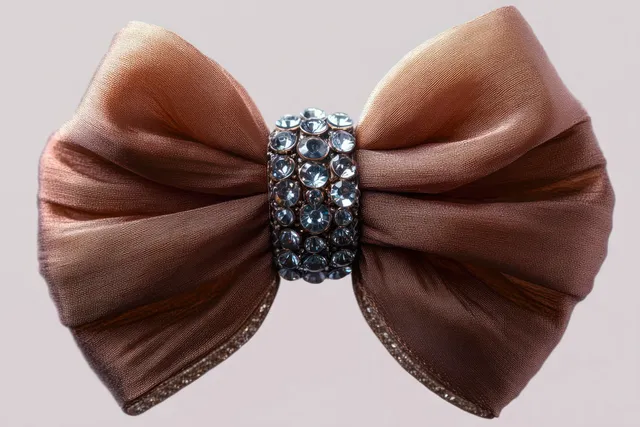 Brown satin bow tied with a rhinestone centerpiece on a soft neutral background.
