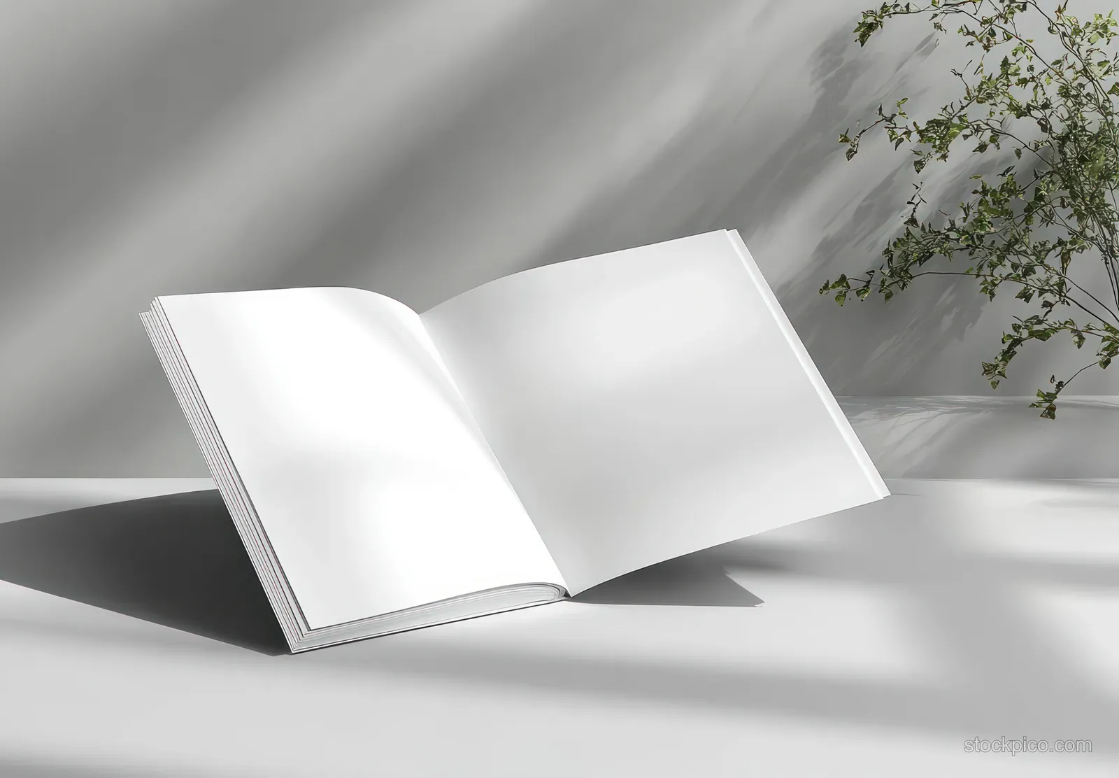 An open blank brochure lies on a gray surface with sunlight and soft plant shadows.