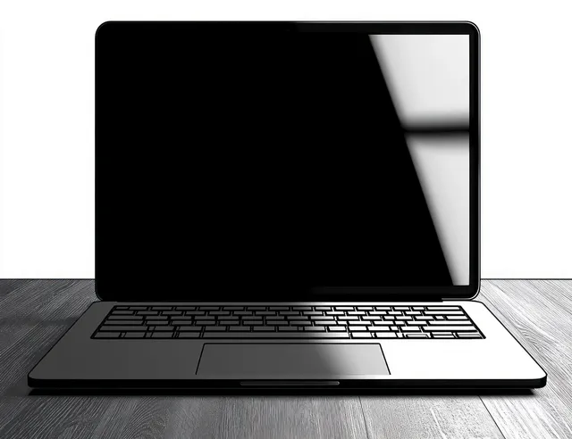 Black laptop with blank screen reflecting window light on wooden desk