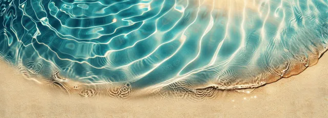 Clear blue water ripples spread over a sandy beach surface with bright sunlight reflections from above.