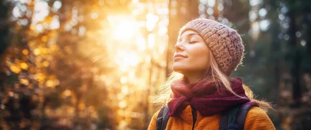 Young woman hiking through sunlit forest, embracing calm nature on a tranquil trail
