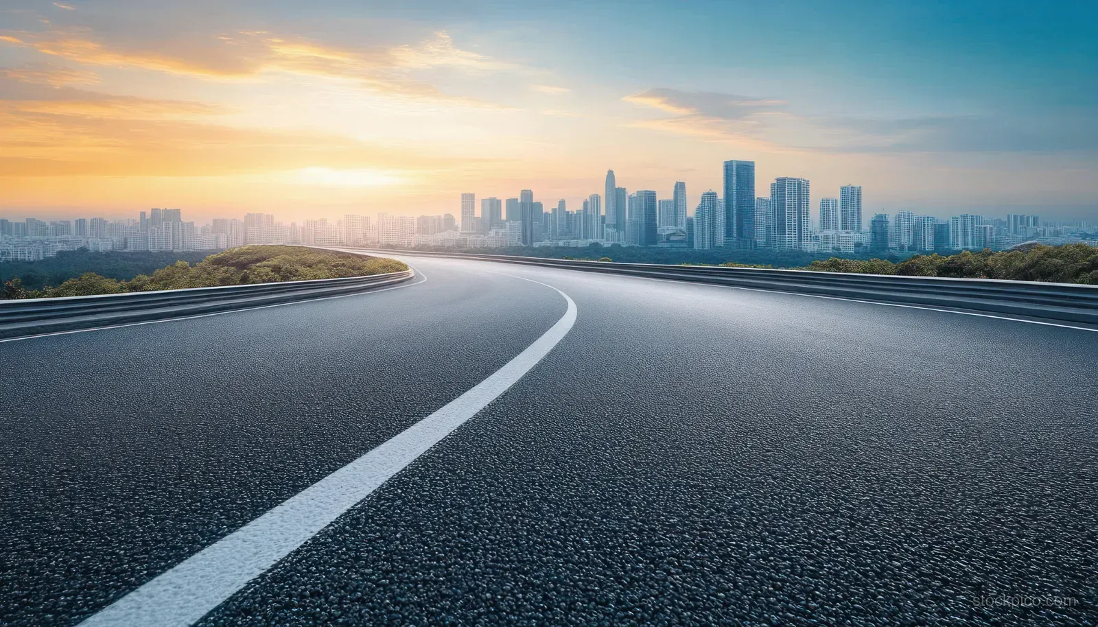 A curving highway stretches toward a distant modern city skyline under golden hour light.