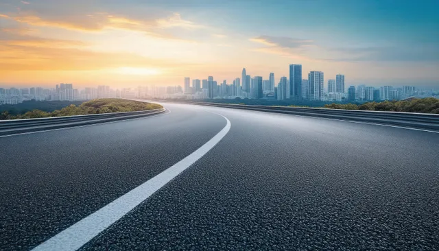 Curving highway leading to distant modern city skyline at golden hour