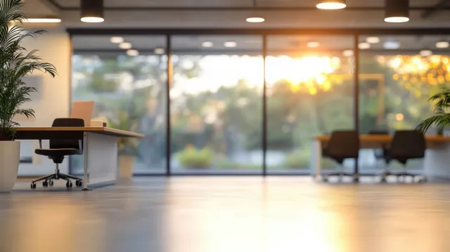 Empty minimalist office with warm ceiling lights, desks, and floor-to-ceiling windows with soft outdoor bokeh.