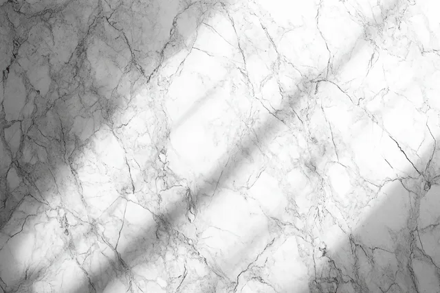 White marble surface with gray natural veining and soft shadows creating a calm textured background.