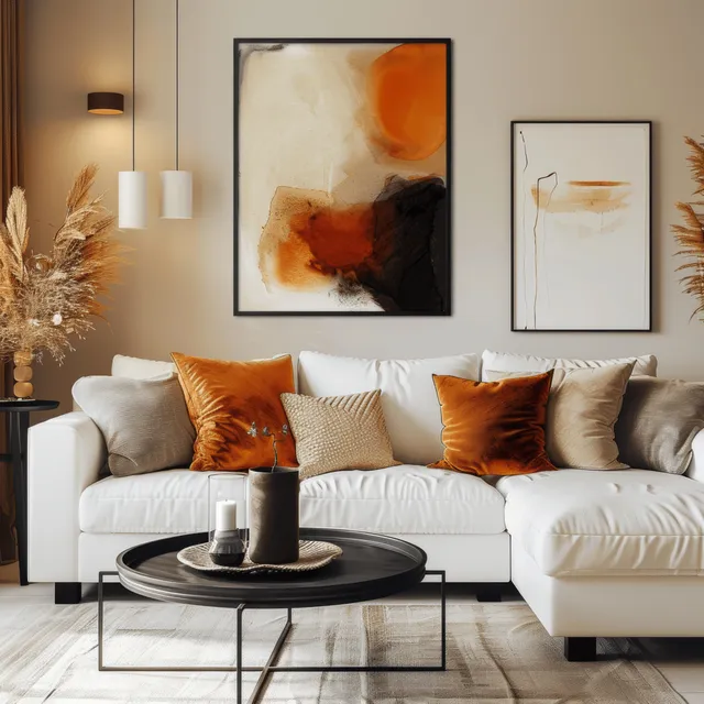 A white sofa with orange pillows sits beneath abstract wall posters beside a black coffee table in a beige living room.