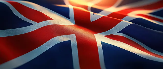 Union Jack flag waves in the breeze with sunlit folds and crisp shadows across the fabric.