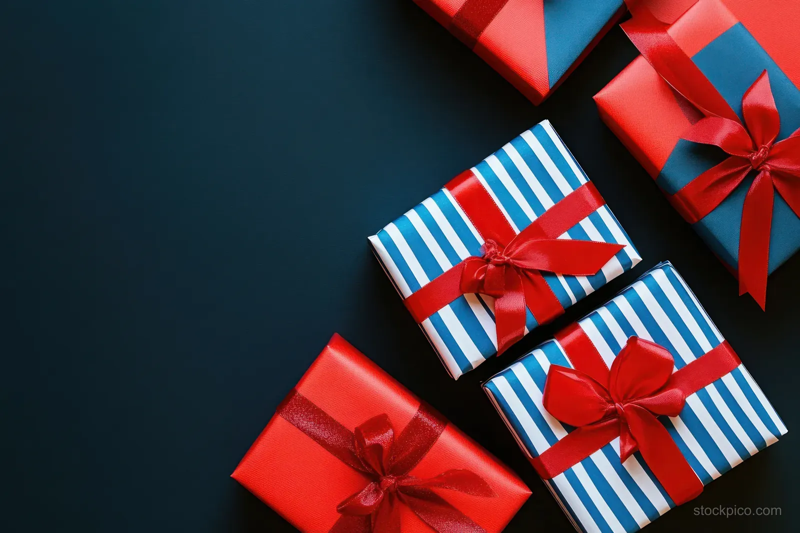 Assorted Independence Day gift boxes with red bows and red white blue stripes sit diagonally on a dark background.