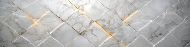 Close-up of a polished marble wall with white and grey veining and thin warm light reflections.