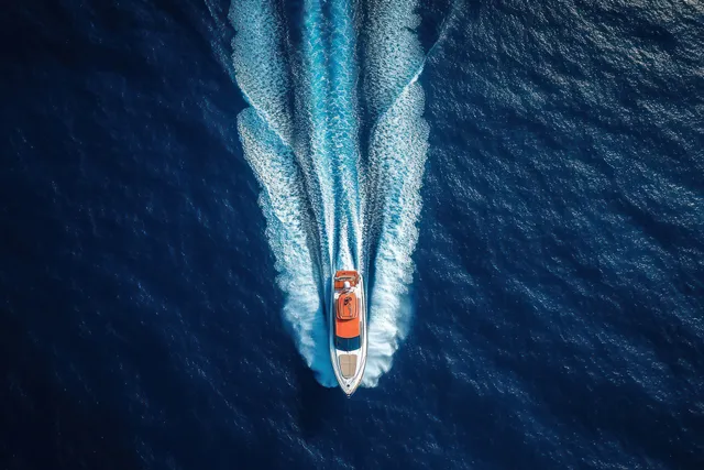Motorboat carving a foamy wake across deep blue ocean under bright sunlight