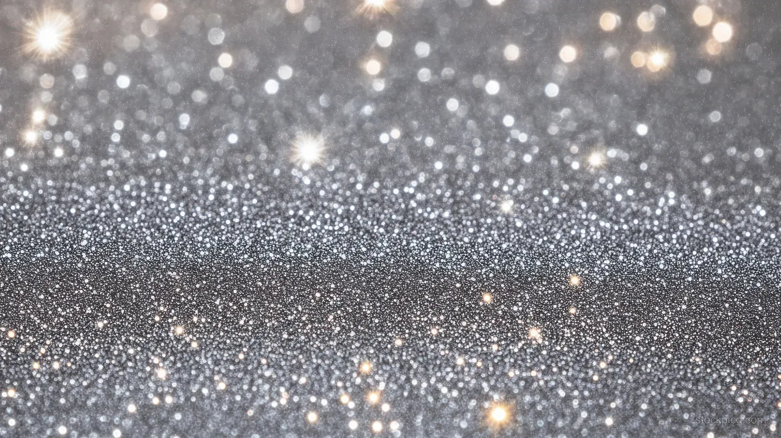 Silver glitter particles sparkle on a dark background with soft glowing bokeh lights.