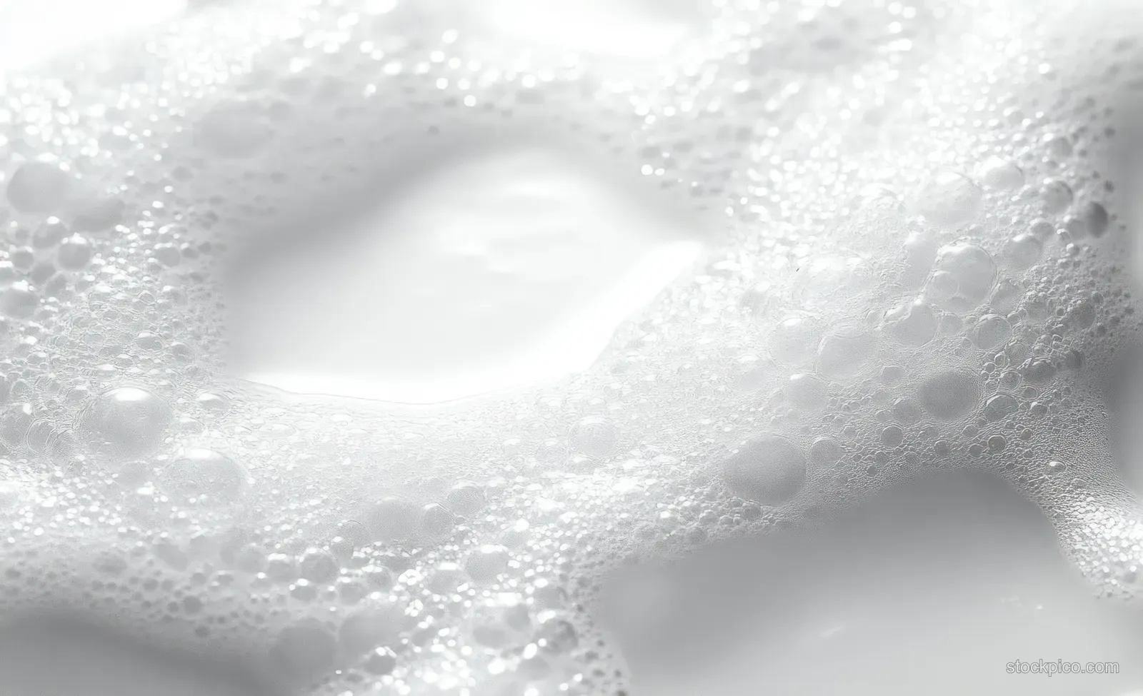 White foam bubbles cluster on a liquid surface, forming soft airy patterns with shimmering reflections.