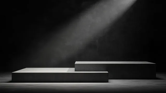 Two rectangular platforms on a dark floor are illuminated by a single spotlight beam, creating long shadows.