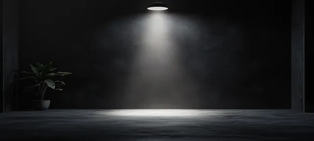 Dramatic spotlight on textured black gray cement wall studio backdrop for product staging