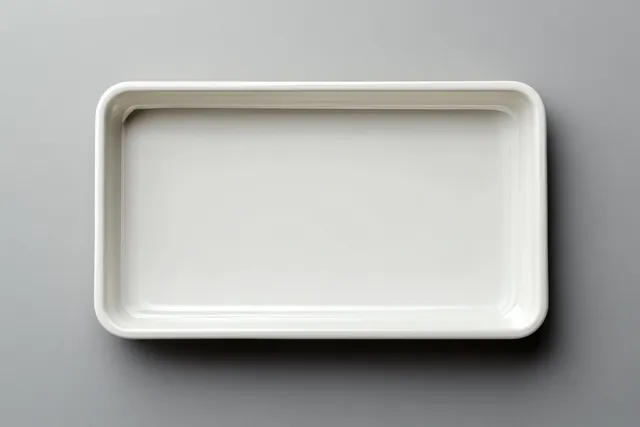 Empty white rectangular food tray placed on a soft grey background in a top-down view.