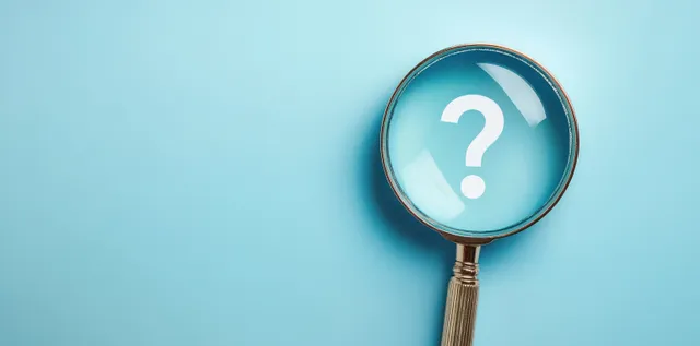 Magnifying glass enlarging a question mark on a light blue background