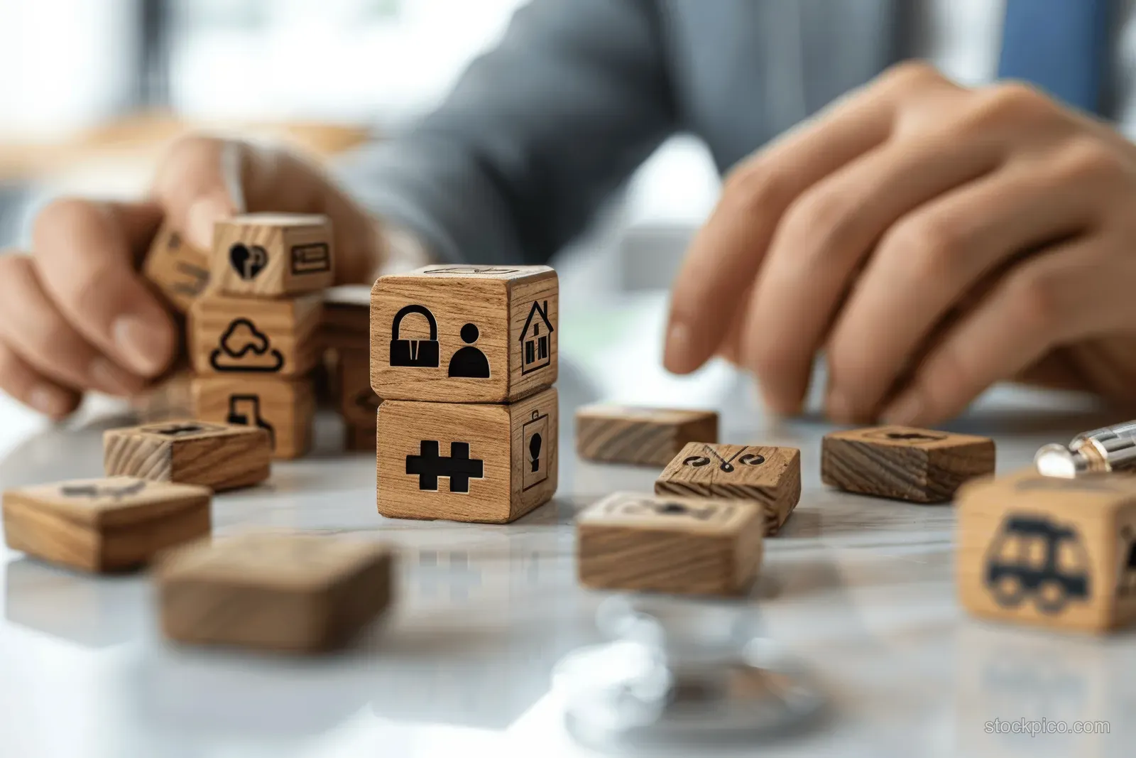 A hand arranges wooden blocks with medical and insurance symbols on a desk.