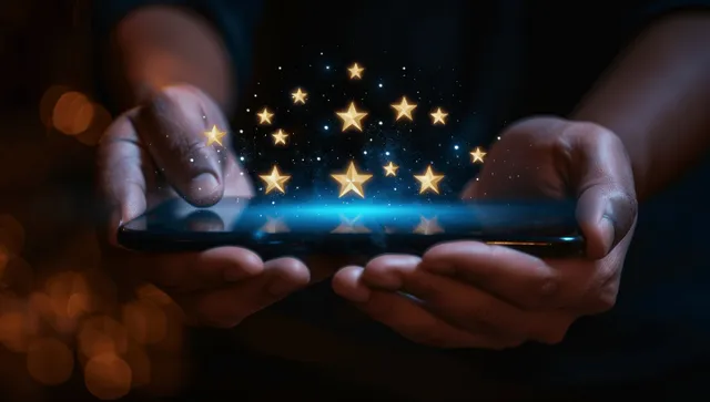Hands hold a smartphone showing glowing five-star rating icons on a dark screen.