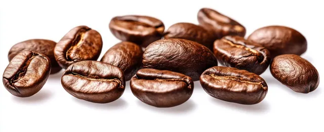 Shiny roasted coffee beans scattered on a white background with visible textured surfaces.