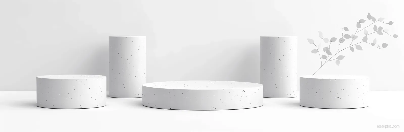 Several white cylindrical podium pedestals arranged on a minimalist studio floor with soft shadows.
