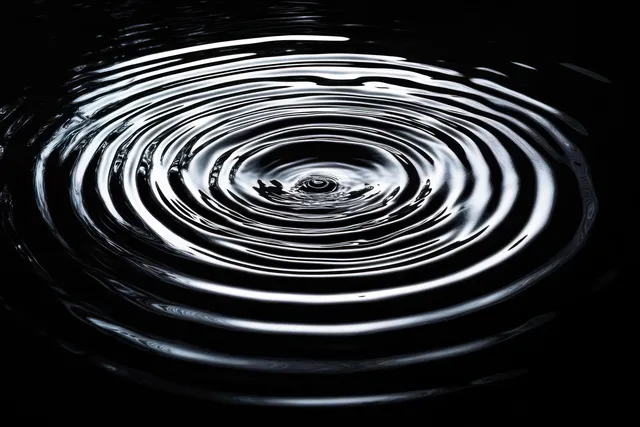 Concentric water ripples on dark surface with bright reflective rings