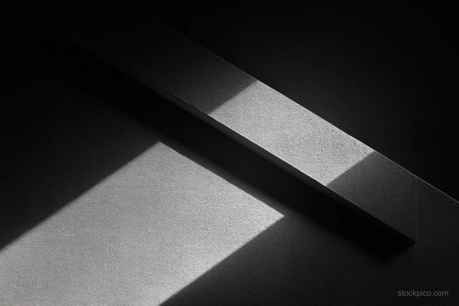 Monochrome concrete wall detail with a dark diagonal bar and sharp shadows across textured surfaces.