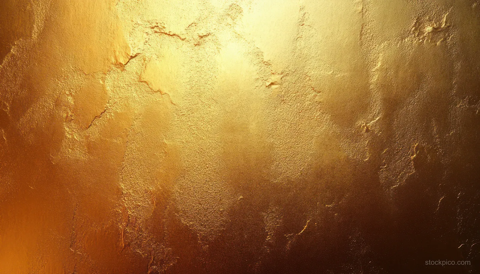 Close-up of a warm textured gold surface with rough uneven patches and shimmering reflective highlights.
