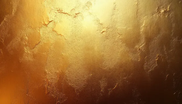 Close-up of a warm textured gold surface with rough uneven patches and shimmering reflective highlights.