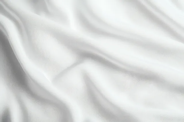Close-up of smooth white fabric with gentle wavy folds and soft shadows.