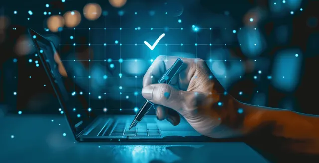 Hand Marks Checkbox on Laptop Screen in a Dark Office