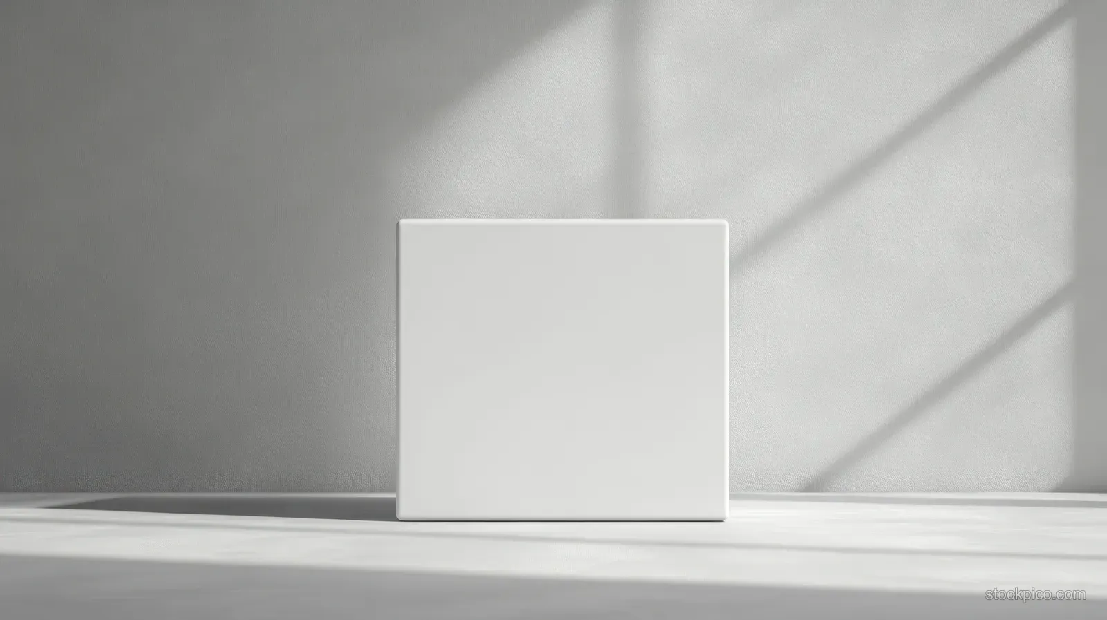 A white cube box sits on a light gray surface with soft diagonal shadows.