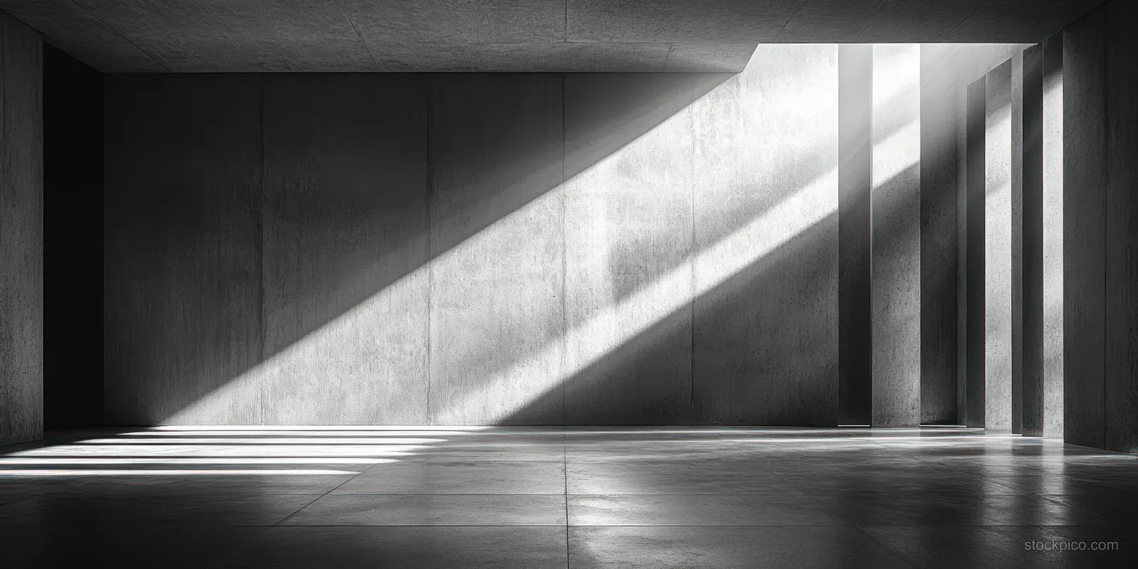 Empty concrete interior room with central ceiling opening casting bright light beams onto a grey floor.