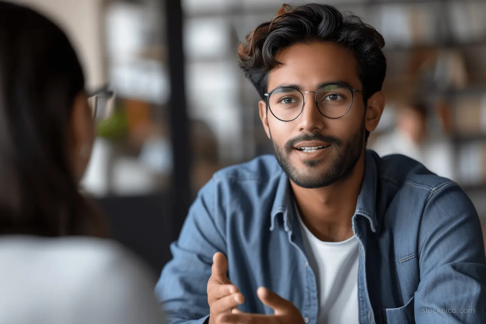 A young Indian entrepreneur and a Western partner engage in a strategy meeting in a modern office environment.