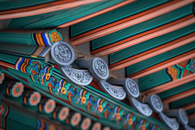 Colorfully painted wooden beams and carved brackets decorate the underside of traditional Korean eaves.