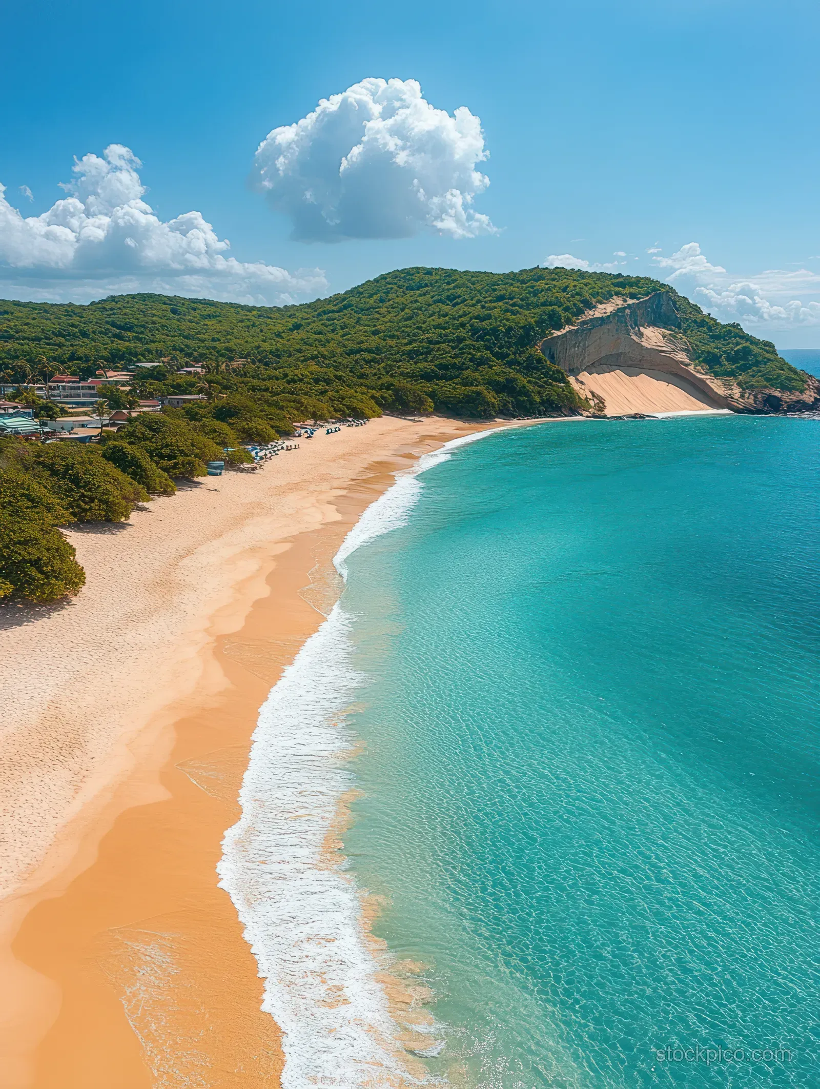 Aerial landscape view shows a curving beach with turquoise water and green hills near Morro do Careca.