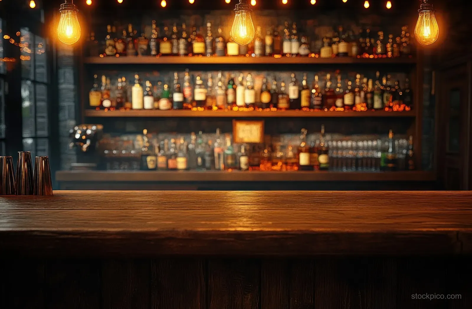 Empty wooden bar counter in a dim pub with warm hanging bulbs and blurred shelves of bottles behind.