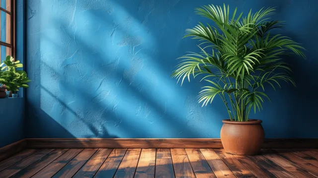 Sunlit wooden floor in a minimalist room with a potted plant beside a dark blue wall.