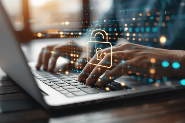 Hands type on a laptop as a glowing digital padlock and network dots appear on the screen.