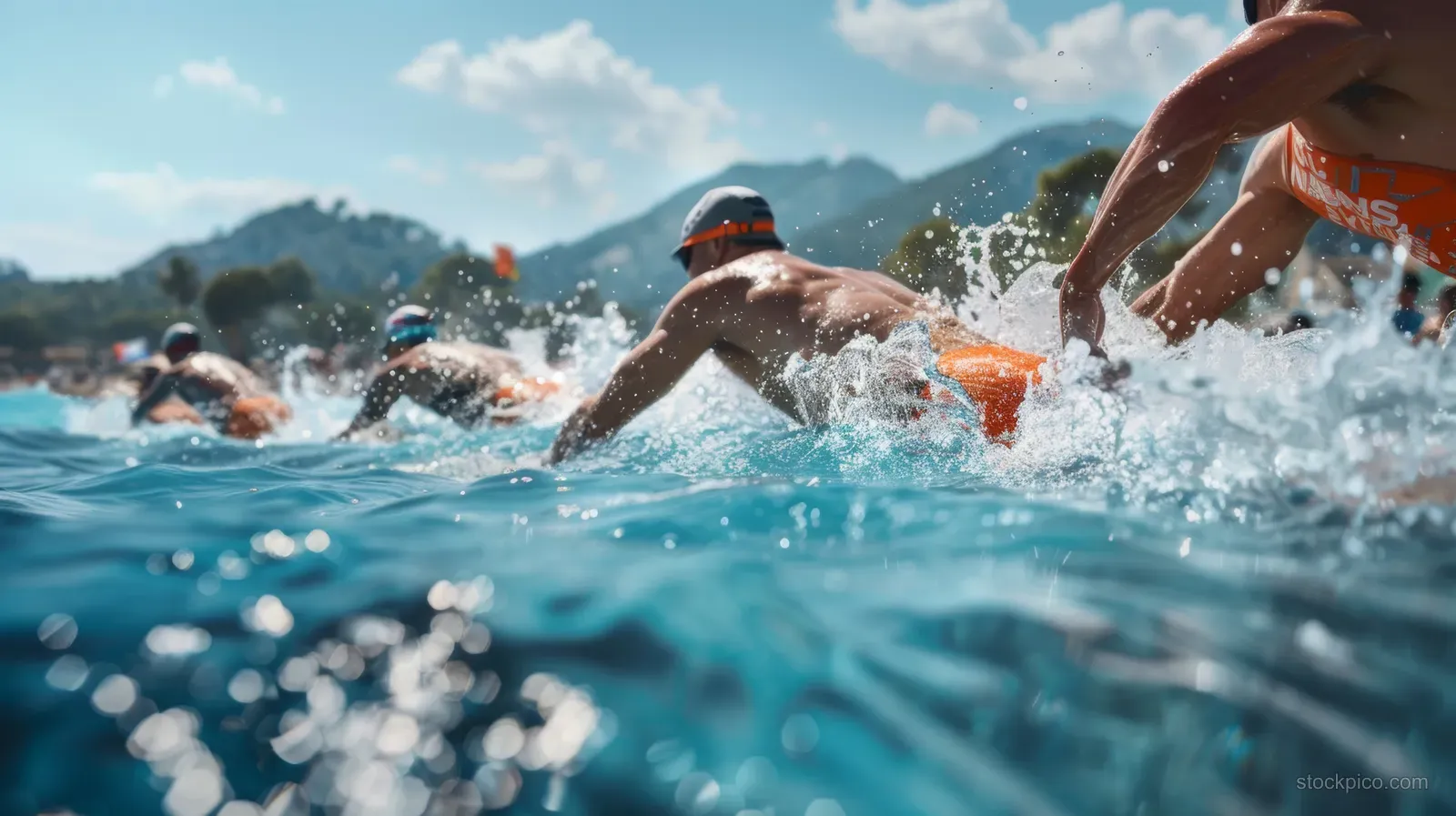 Triathletes dive into clear blue ocean water, splashing as they begin a coastal sprint race.