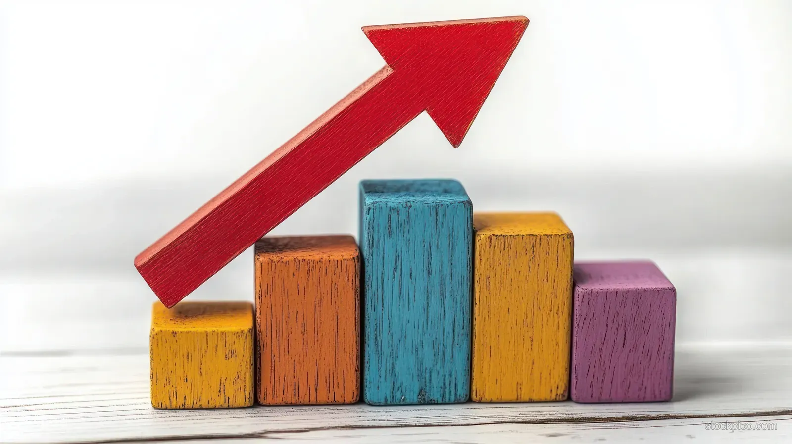 Colorful wooden blocks form a bar chart with a large red arrow pointing upward.