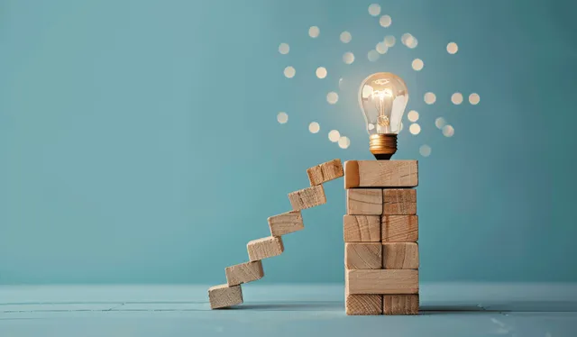 Wooden block ladder rising to a glowing lightbulb symbolizing problem solving