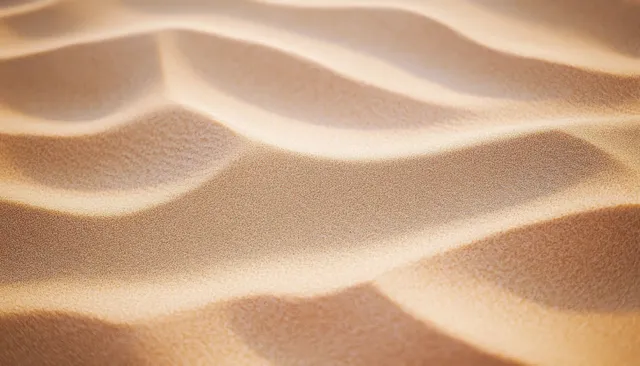 Sunlit desert sand dunes close-up showing smooth ripples and soft shadows across curved ridges.