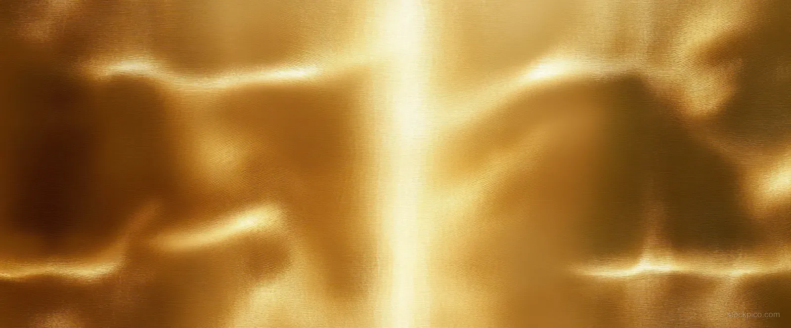 Close-up of a polished gold metal surface with reflective highlights and shadowed ridges.